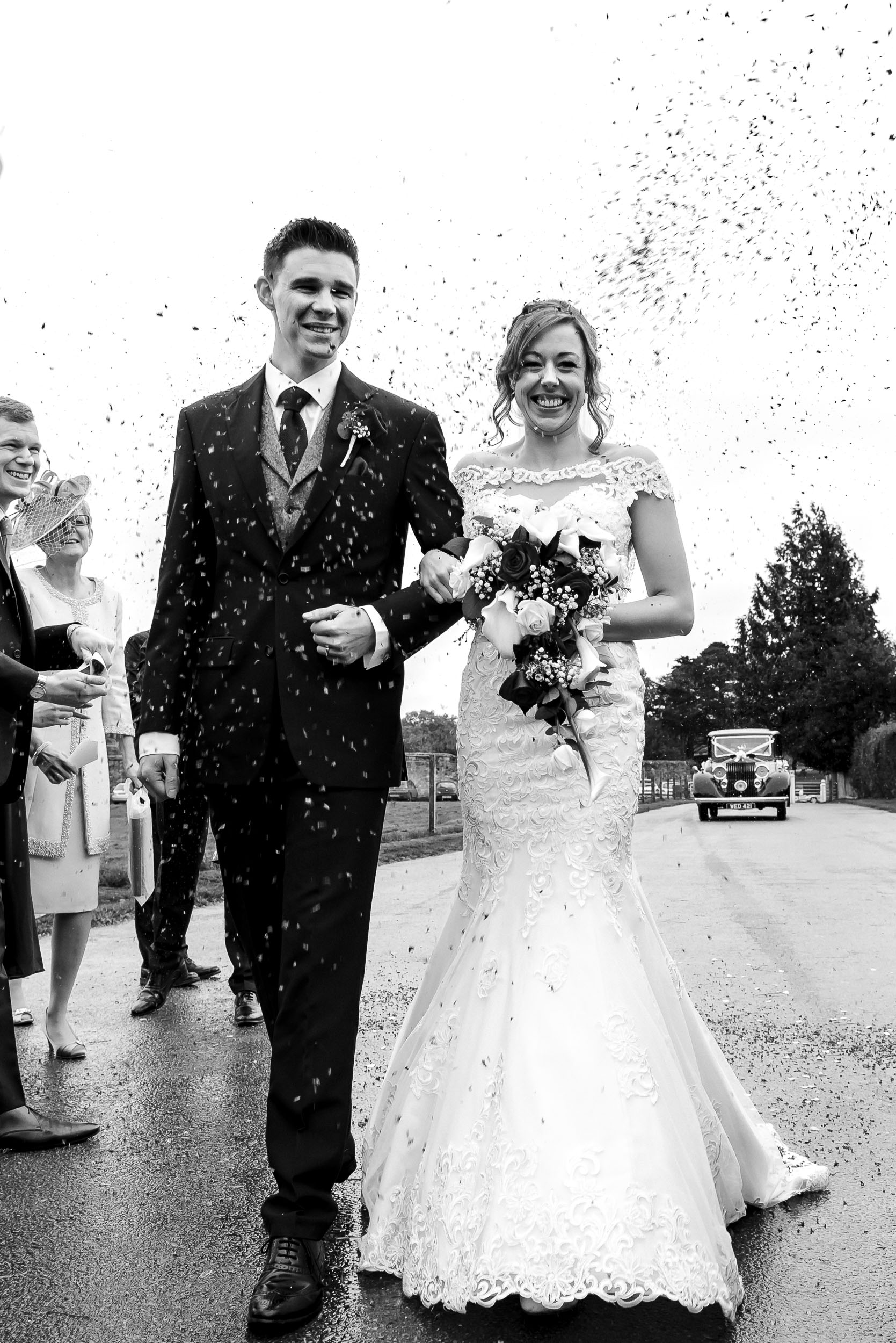 Bride and groom walking while being shower in confetti at The Domus, Beaulieu, Hampshire