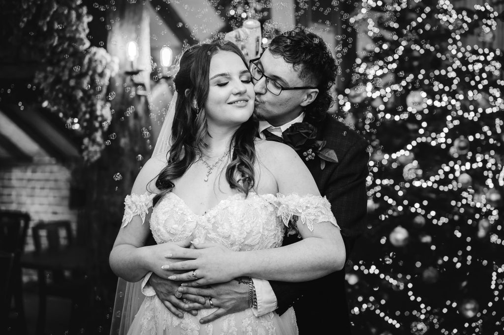 Bride and groom in front of a Christmas tree at The Moat at Wrotham, Kent wedding