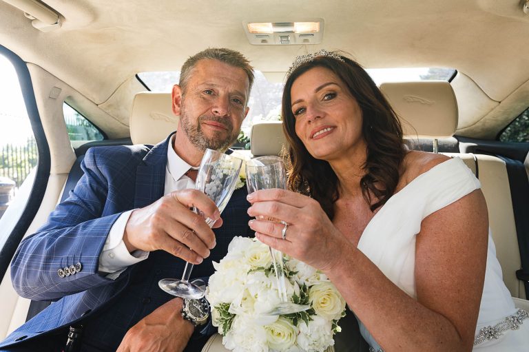Bride and groom raising a glass of champagne in the back of their wedding car, supplied by Three Kings Wedding Cars of Sidcup, Kent