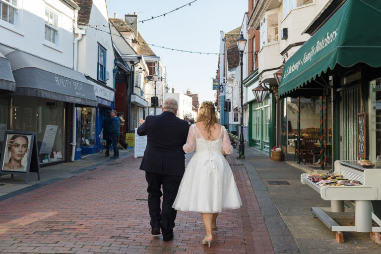Bride and father walking through Faversham town centre on the way to the wedding ceremony | Oakhouse Photography
