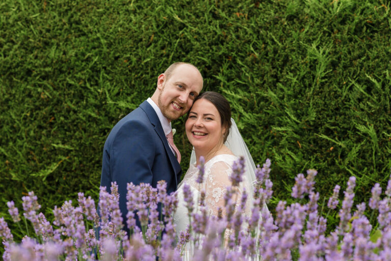 Bride and groom posing behind lavender bush at Swallows Oast wedding venue, Ticehurst, East Sussex | Oakhouse Photography