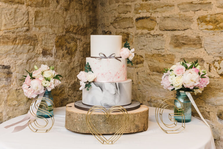 Wedding cake and floral bouquets on display at Swallows Oast wedding venue, Ticehurst, East Sussex | Oakhouse Photography