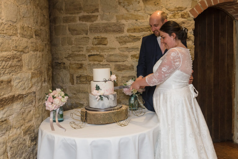 Bride and groom cutting the wedding cake at Swallows Oast wedding venue, Ticehurst, East Sussex | Oakhouse Photography
