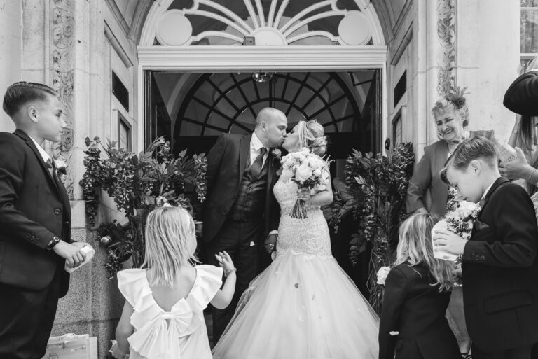 Bride and groom kissing on the steps of Chelsea Old Town Hall, King’s Road, London | Oakhouse Photography