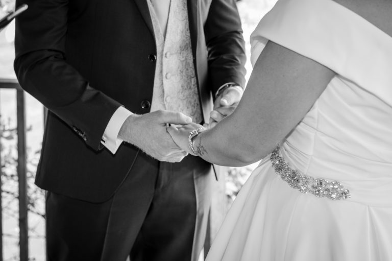 Close-up photo of bride and groom holding hands during ceremony at Mercure Maidstone Great Danes Hotel wedding