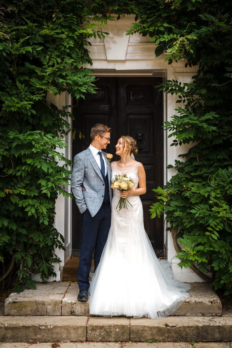 Portrait of bride and groom in front of main doorway at Sprivers Mansion wedding venue, Kent