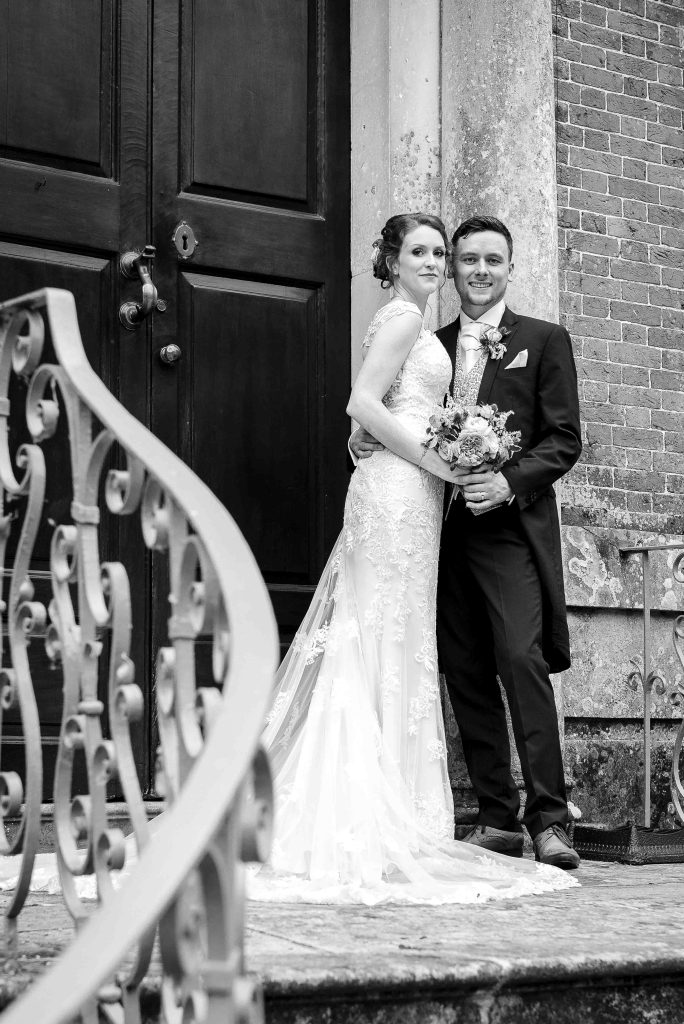 Bride and groom standing on steps of Manor House at a New Forest, Hampshire wedding