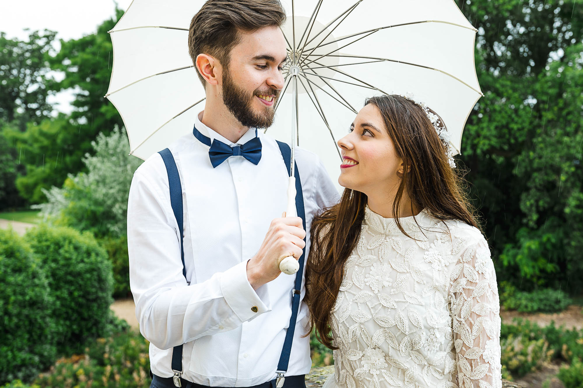 Bride and groom portrait at the top of the steps of Danson House, Danson Park, Bexleyheath, Kent while holding a parasol umbrella in the rain