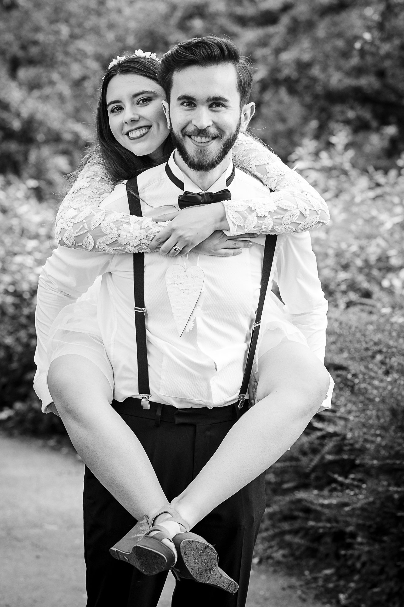 Groom giving a piggyback to bride in grounds of Danson Park, Bexleyheath