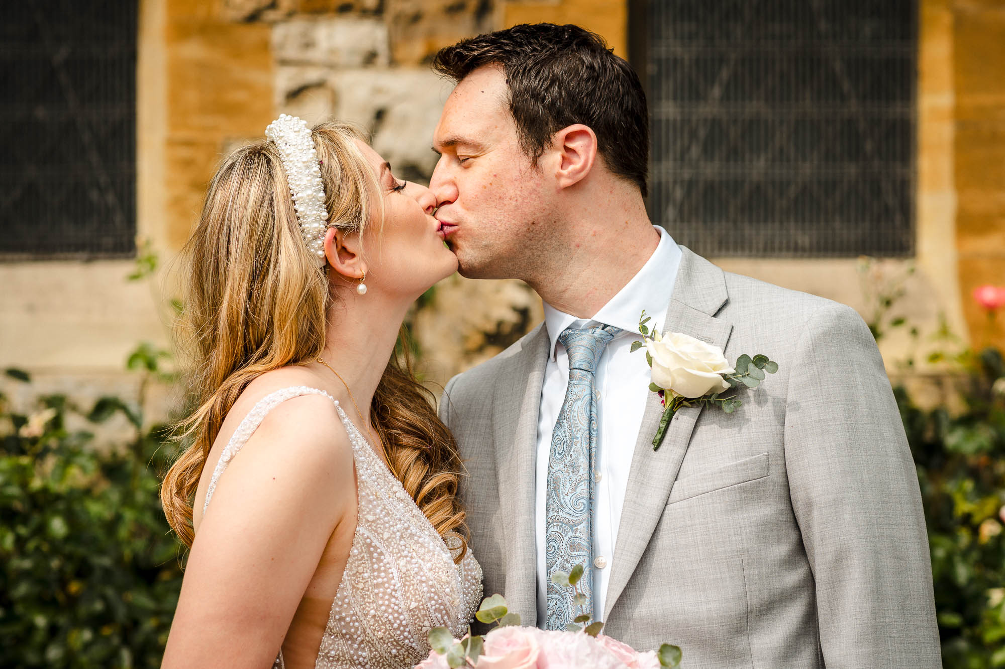 Bride and groom kissing in the grounds of St John the Baptist Church in Eltham, London