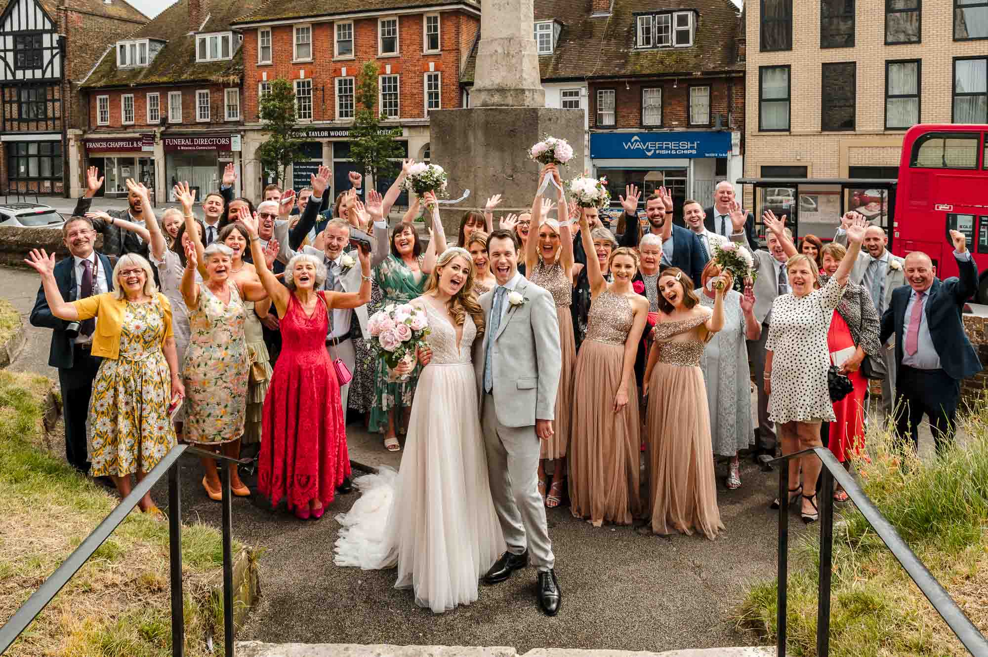 Group shot of the entire wedding party in the grounds of St John the Baptist Church in Eltham, London