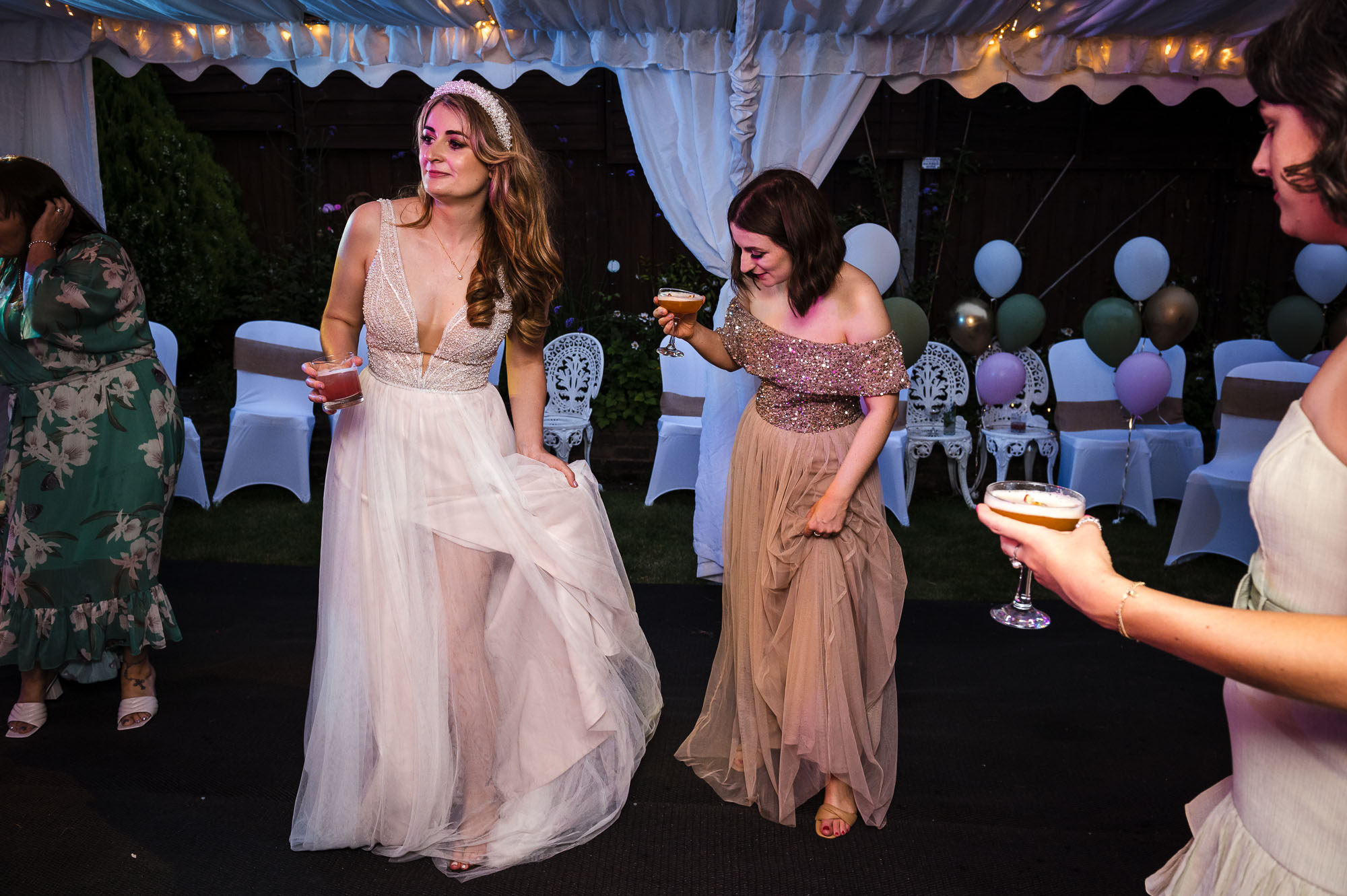 Bride dancing with bridesmaids and drinking cocktails at a marquee wedding reception in Eltham, London