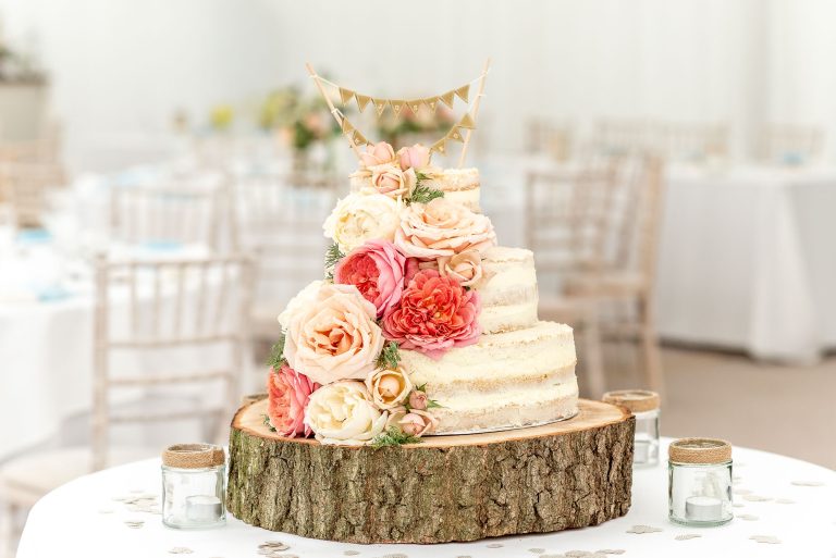 Three tier naked wedding cake with ivory & peach roses for decoration