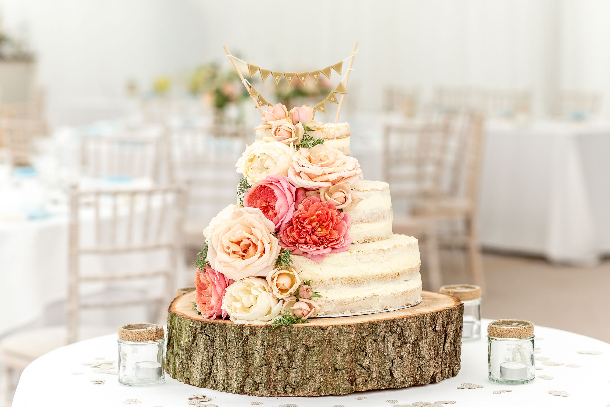 Three tier naked wedding cake with ivory & peach roses for decoration