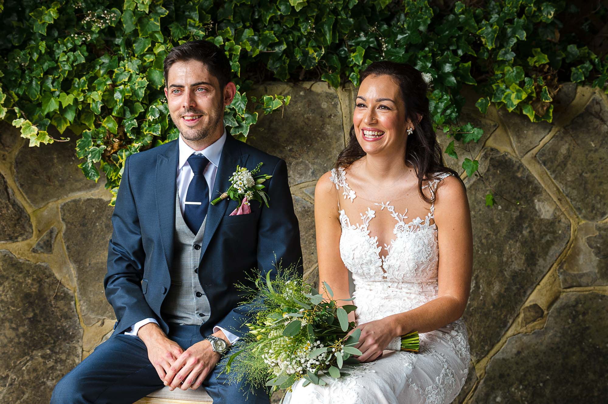 Bride and groom sitting down listening to the registrar under The Pavilion at their Swallows Oast wedding venue in Ticehurst, East Sussex