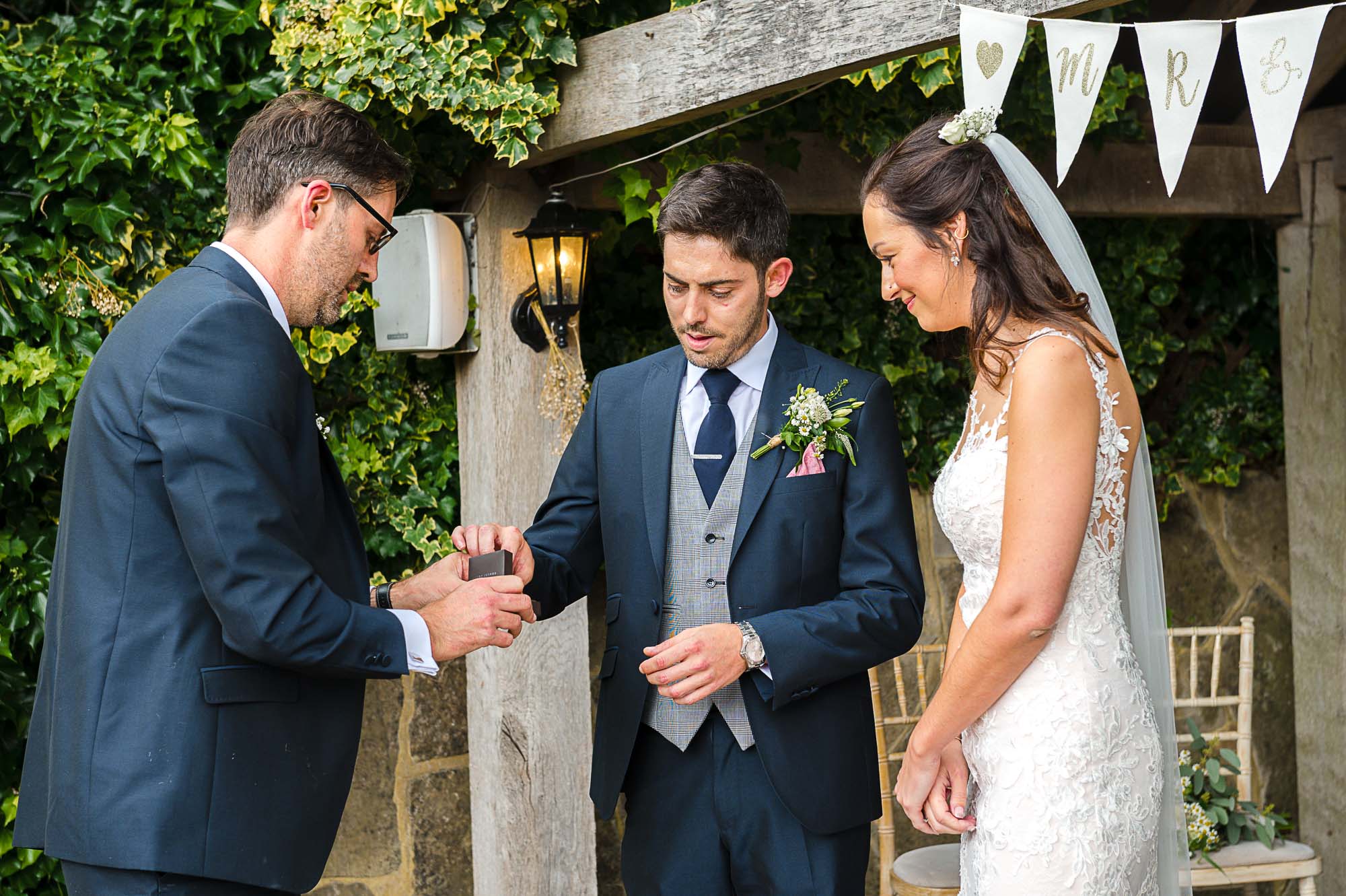 Groom accepting the ring from the best man during the exchanging of rings at The Pavilion at their Swallows Oast wedding venue in Ticehurst, East Sussex