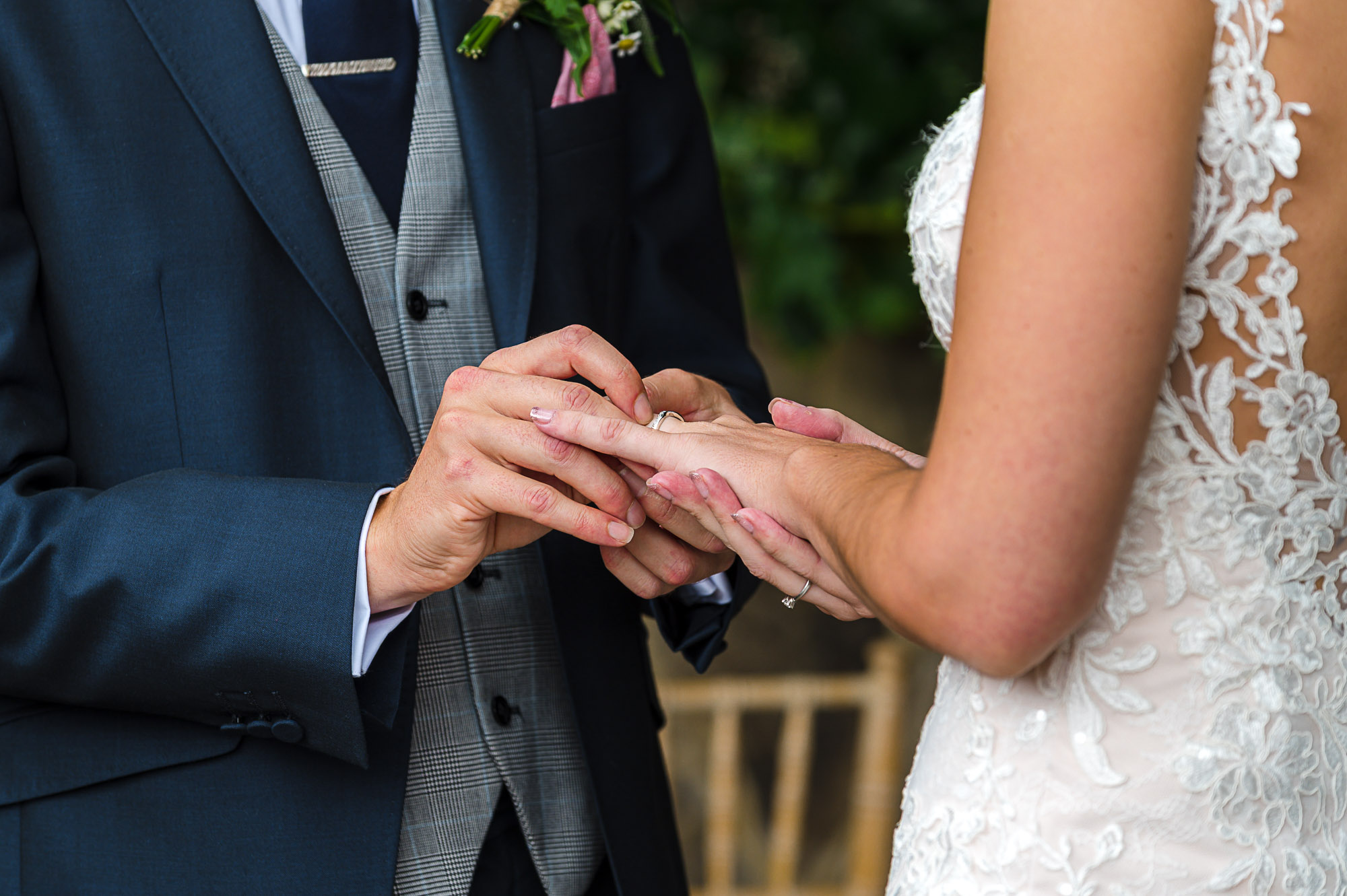Close-up of the exchanging of rings between the bride and groom under The Pavilion at their Swallows Oast wedding venue in Ticehurst, East Sussex