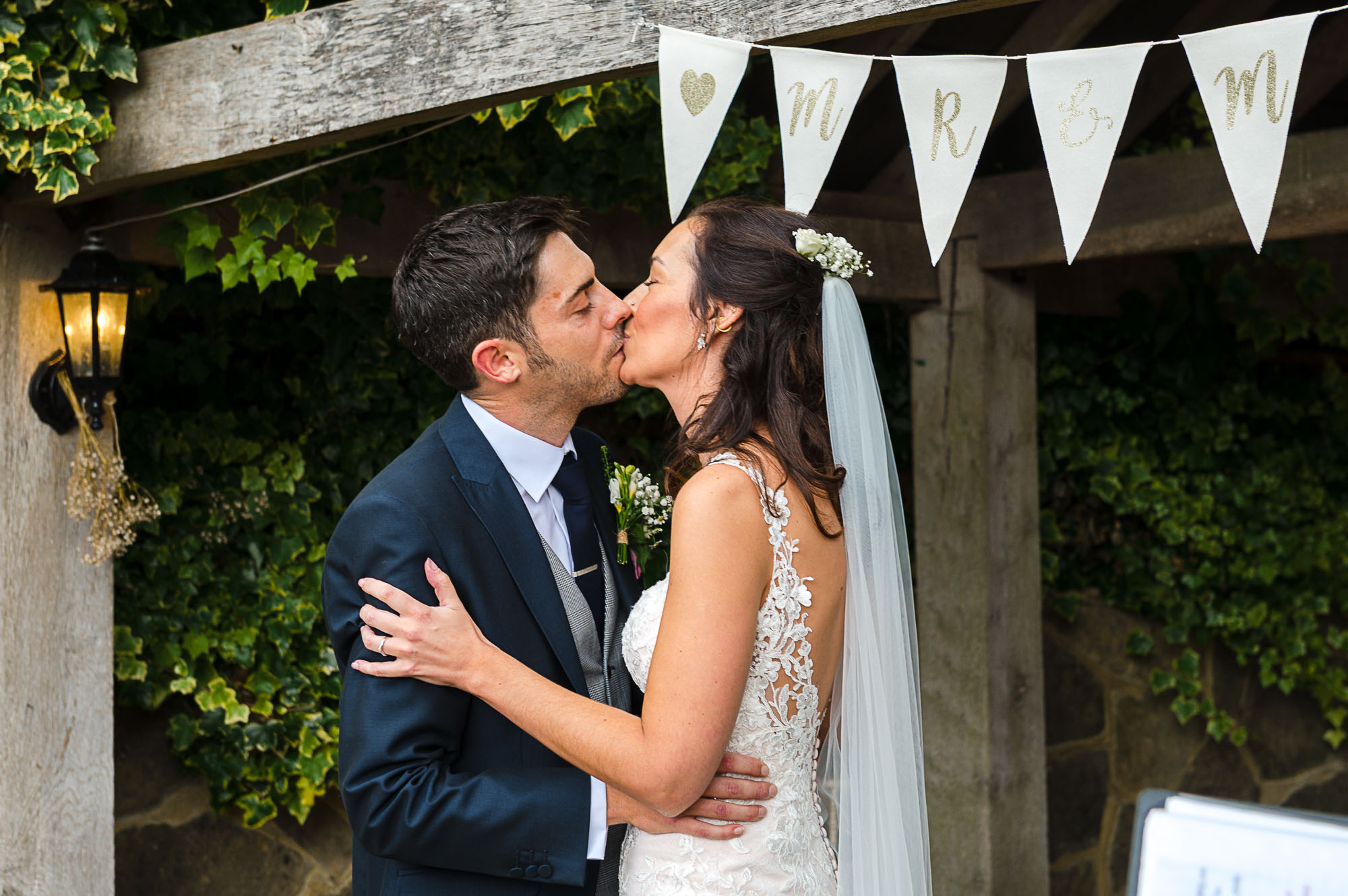 Bride and groom kissing after getting married under The Pavilion at their Swallows Oast wedding venue in Ticehurst, East Sussex