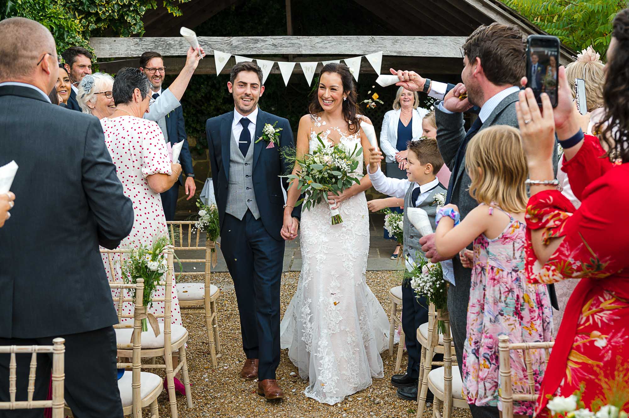 Bride and groom walking down the aisle after their outdoor wedding ceremony at their Swallows Oast wedding venue in Ticehurst, East Sussex