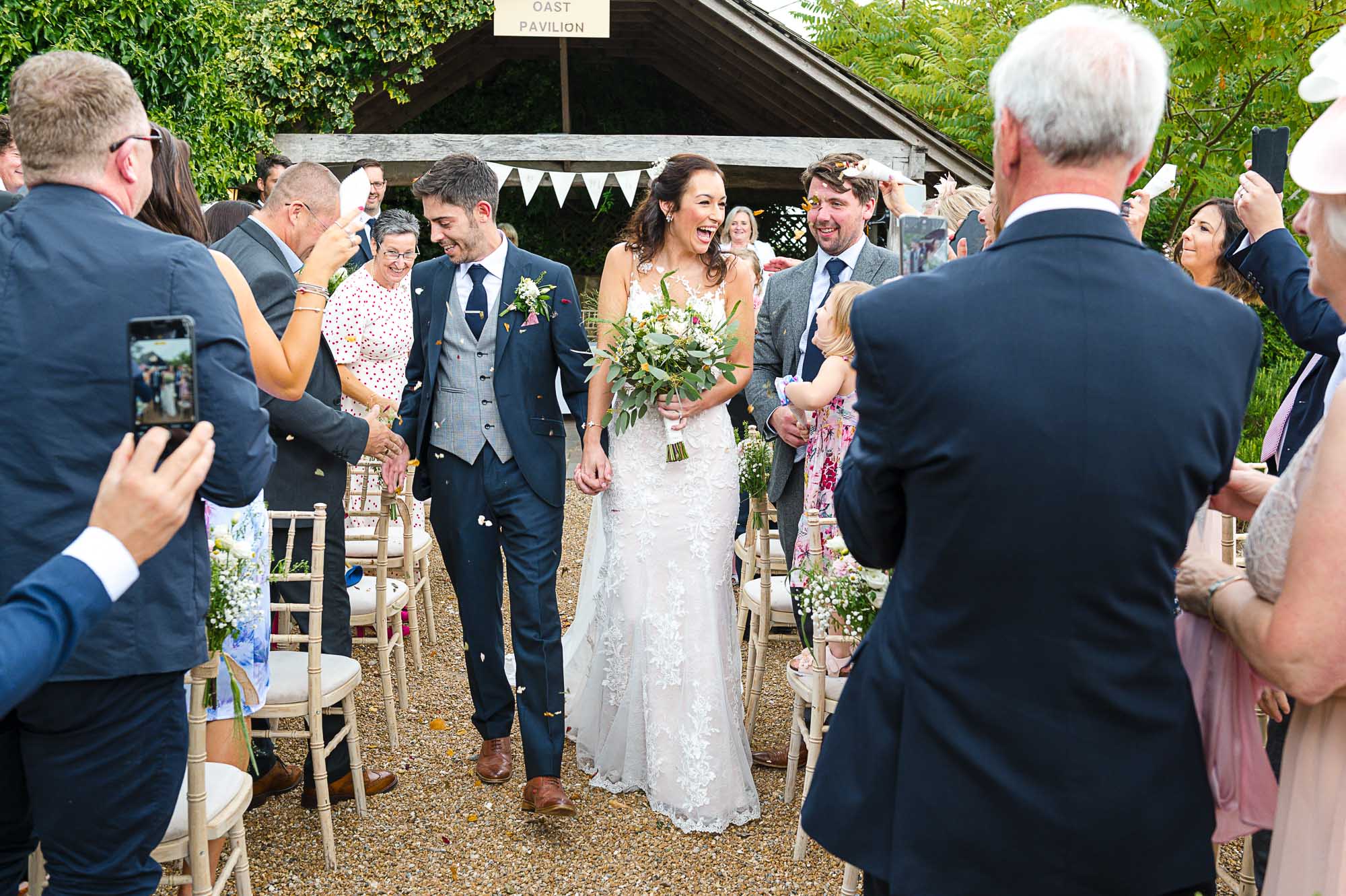 Bride and groom walking down the aisle after their outdoor wedding ceremony at their Swallows Oast wedding venue in Ticehurst, East Sussex