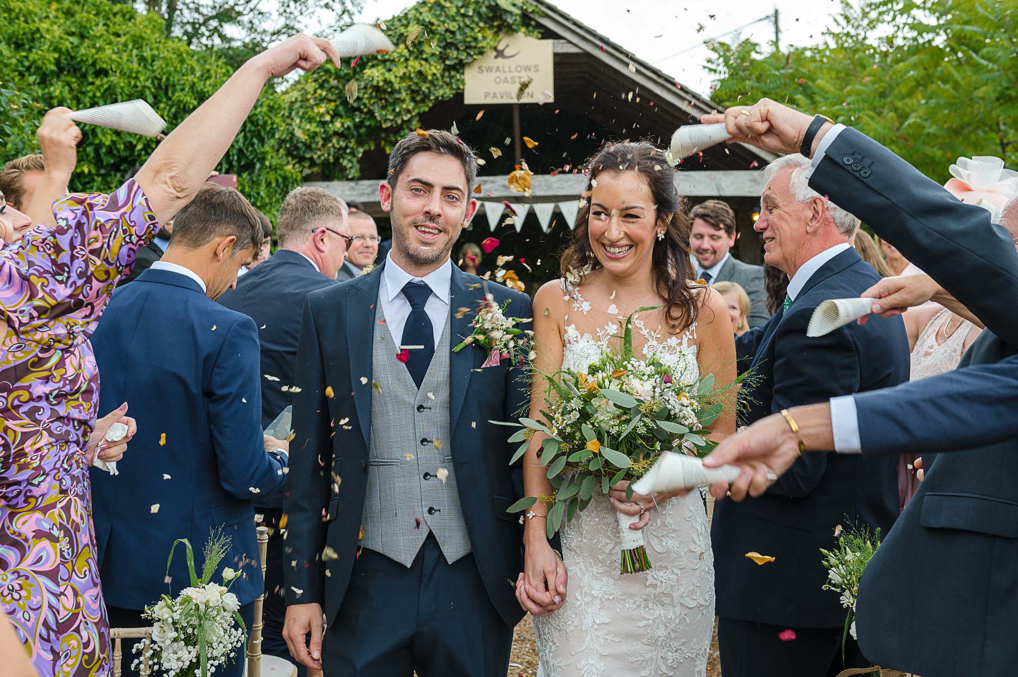 Bride and groom being showered in confetti at their Swallows Oast wedding venue in Ticehurst, East Sussex