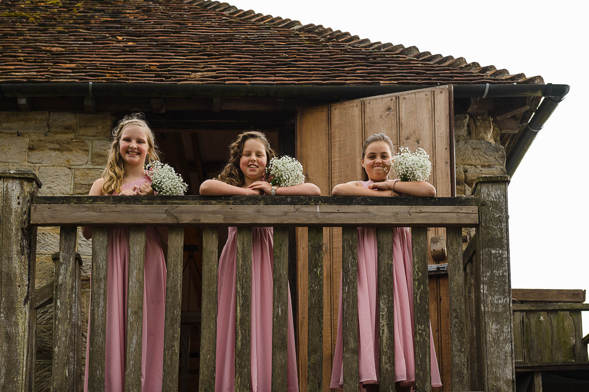 Candid documentary photograph of flower girls on top of stairs at Swallows Oast wedding venue in Ticehurst, East Sussex