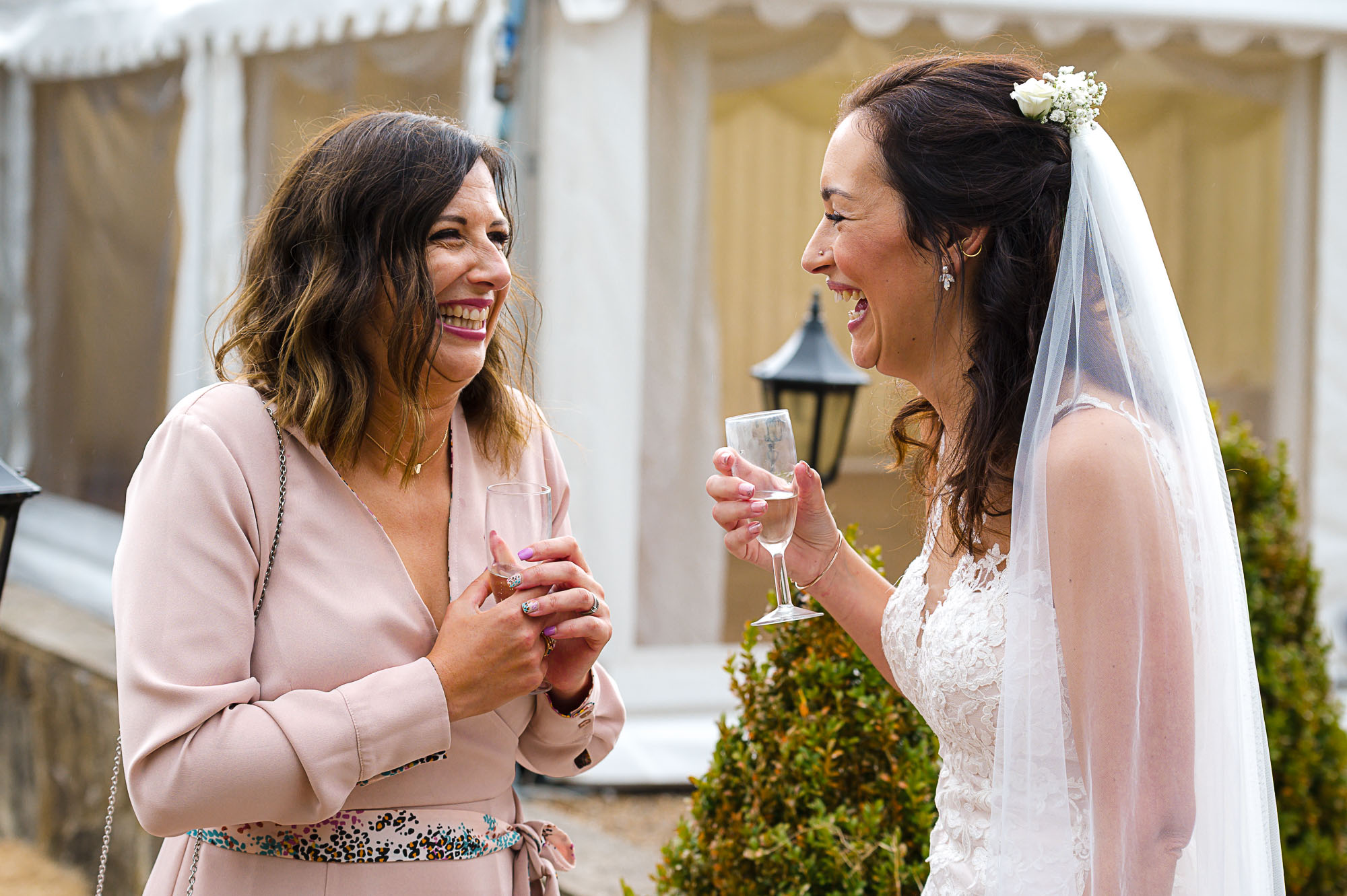 Bride sharing a laugh with guest at Swallows Oast wedding venue in Ticehurst, East Sussex