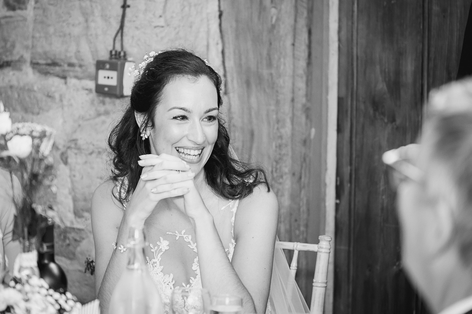 Candid documentary portrait of bride and wedding party during the groom's speech during the reception at Swallows Oast wedding venue, Ticehurst, East Sussex