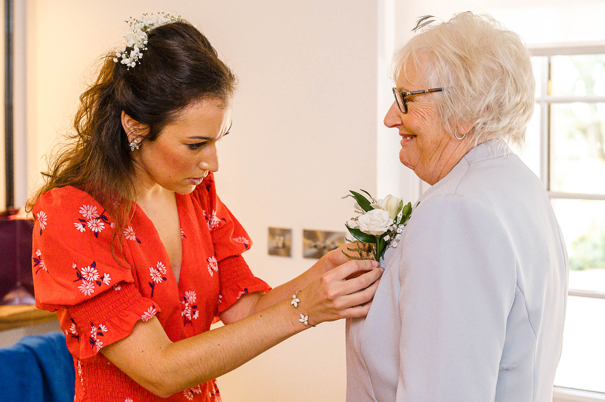 Bride adding a flower to her mother's jacket during bridal prep in The Bridal Suite at Swallows Oast wedding venue in Ticehurst, East Sussex