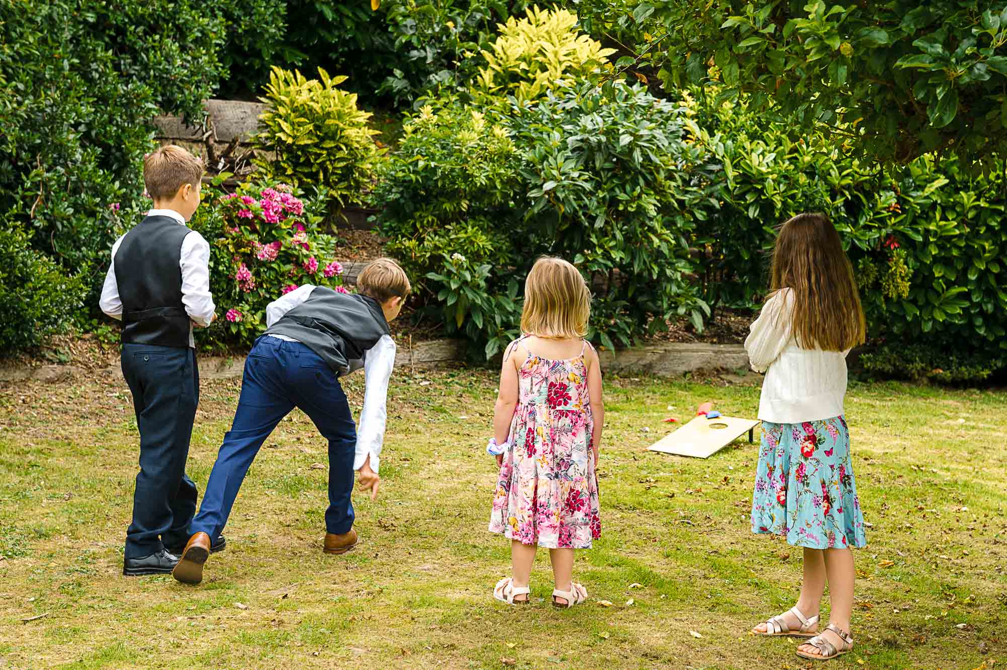 Children playing lawn games and throwing bean bags before the wedding ceremony at Swallows Oast wedding venue in Ticehurst, East Sussex