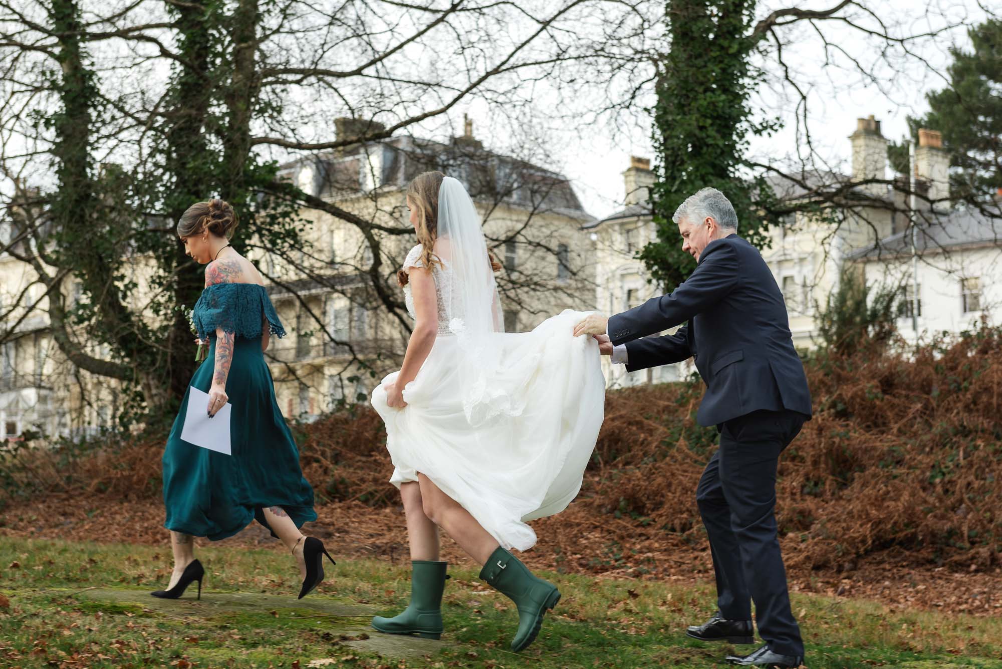 Bride being assisted back to her wedding car while wearing Wellington boots