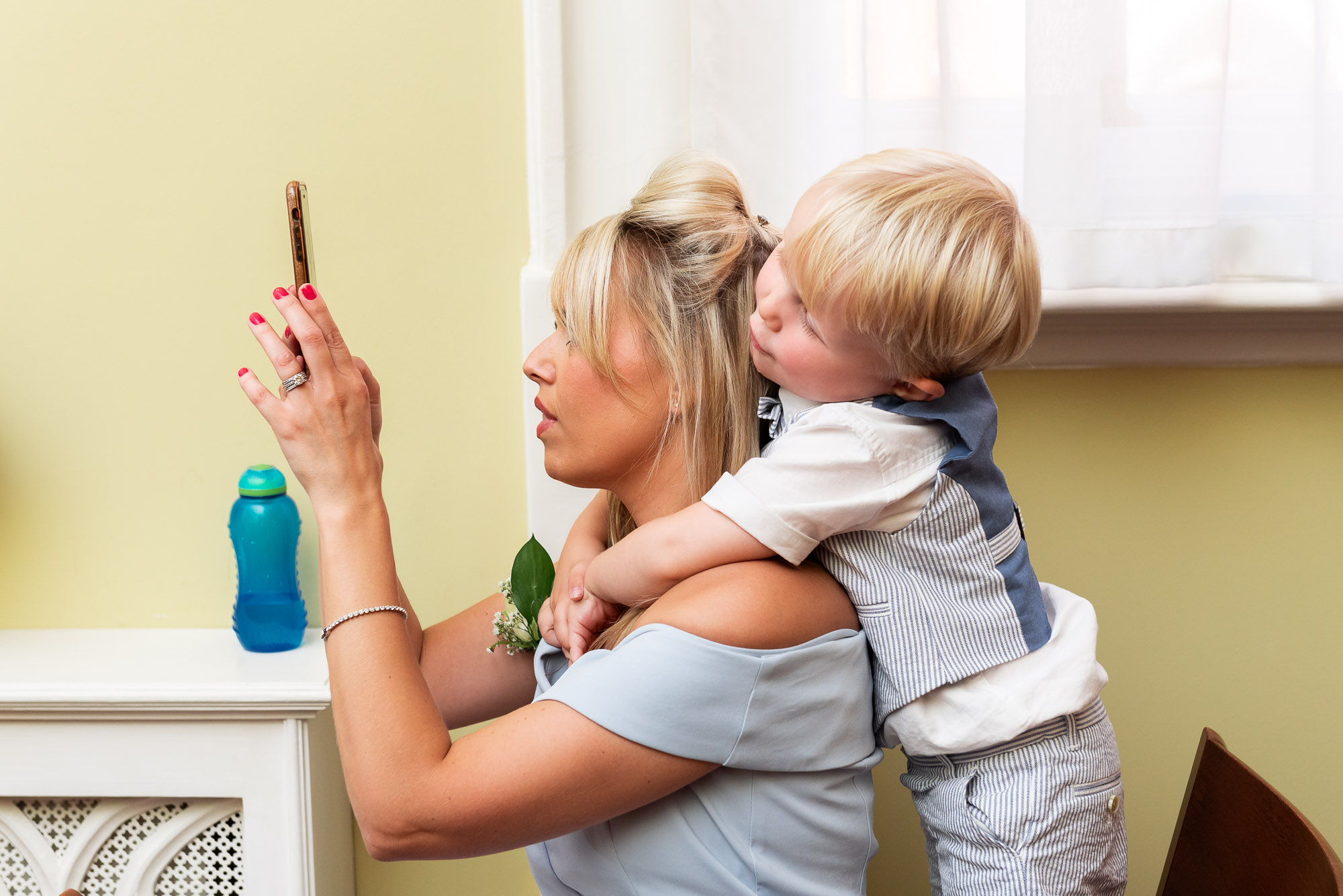 Wedding guest with child holding onto her taking a photo of the bride and groom at Chelsea Old Town Hall wedding