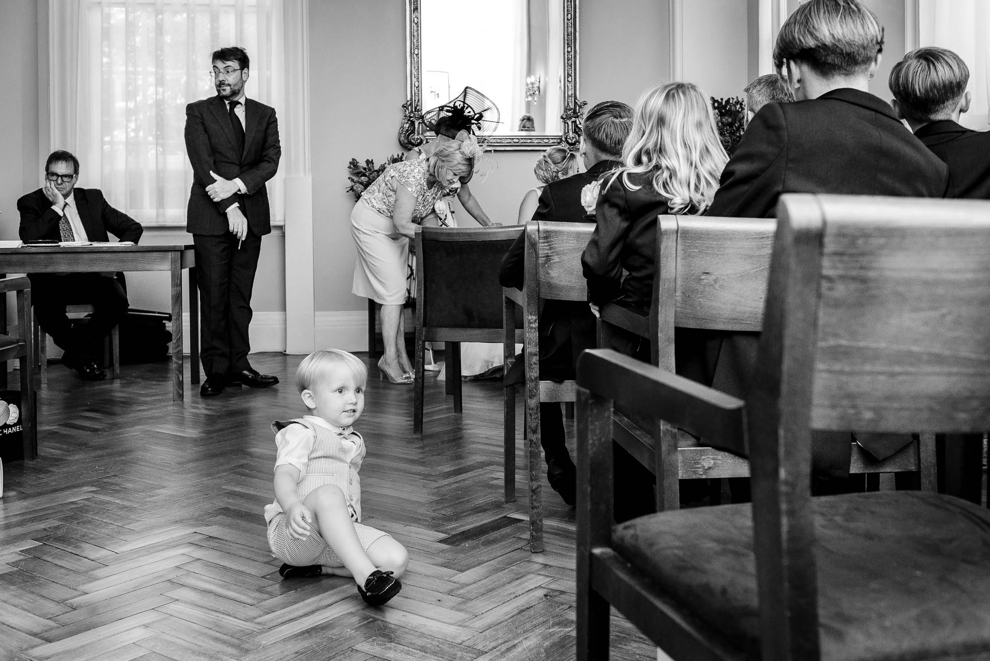 Child sitting in the centre of the registry office floor during the register signing at Chelsea Old Town Hall wedding