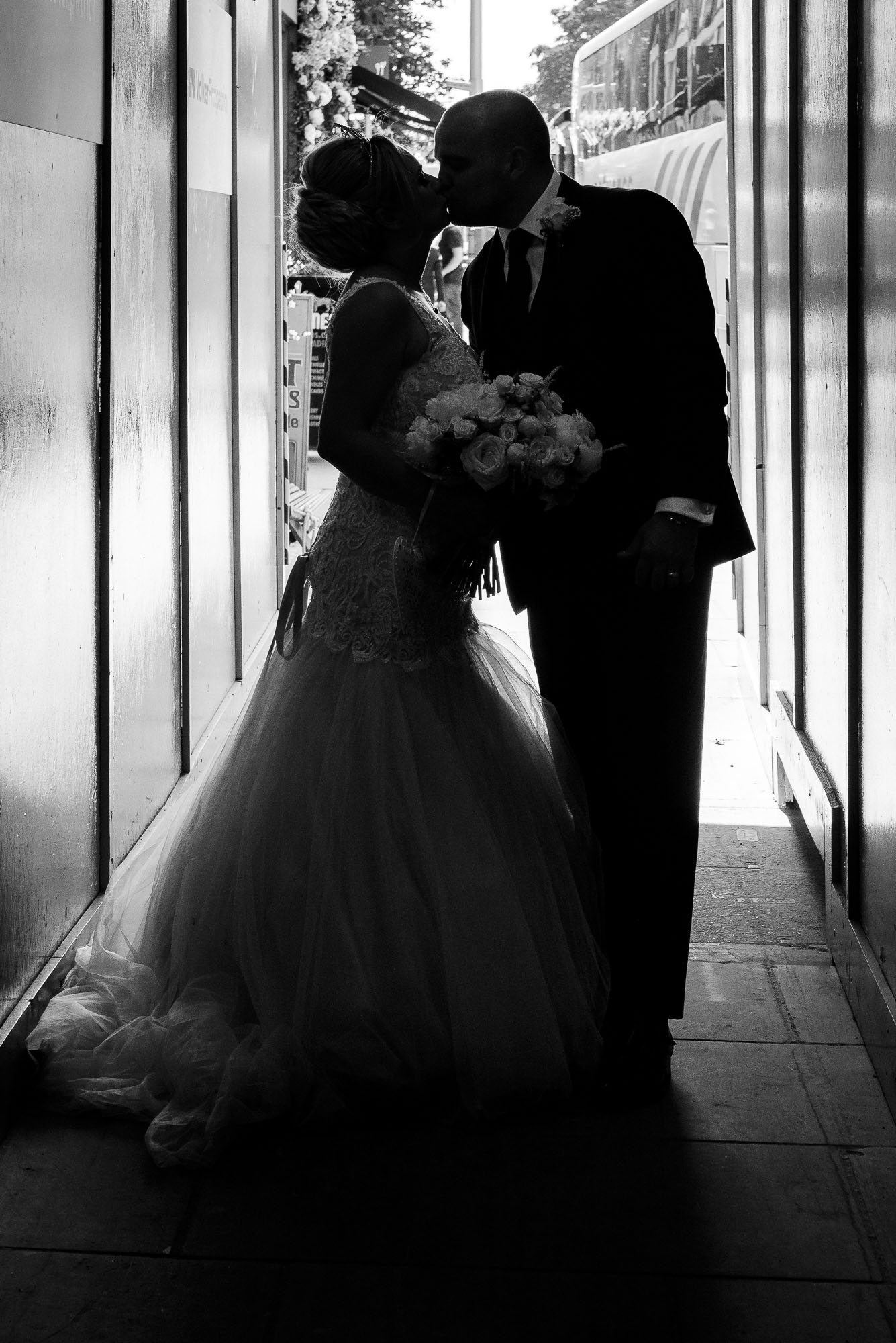 Bride and groom kissing on walk down the King's Road to Bluebird Chelsea wedding reception