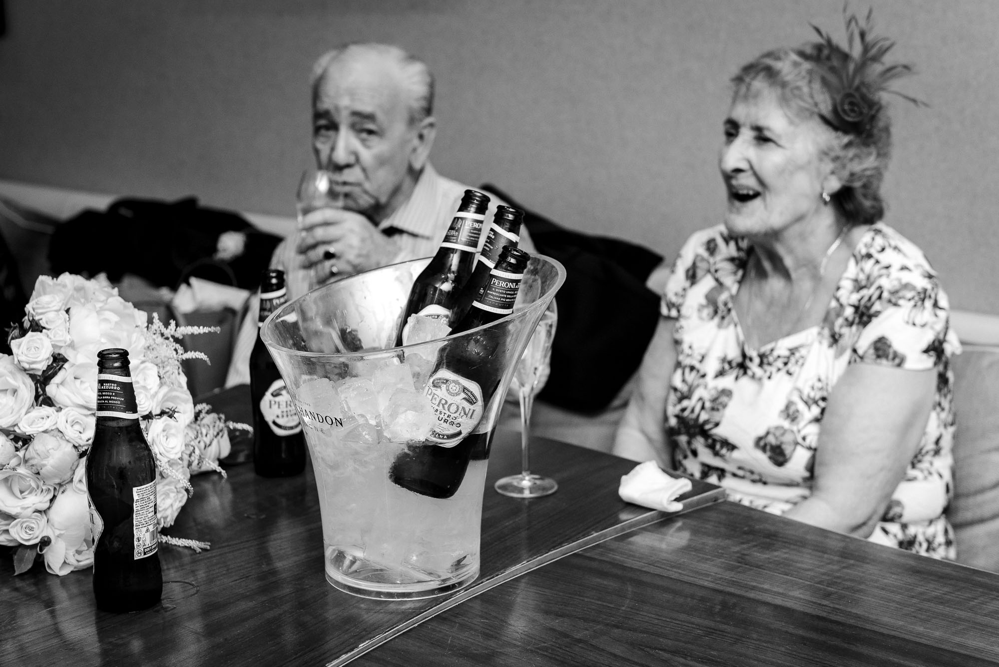 Documentary photo of bottles of beer in ice bucket with guests behind at Bluebird Chelsea