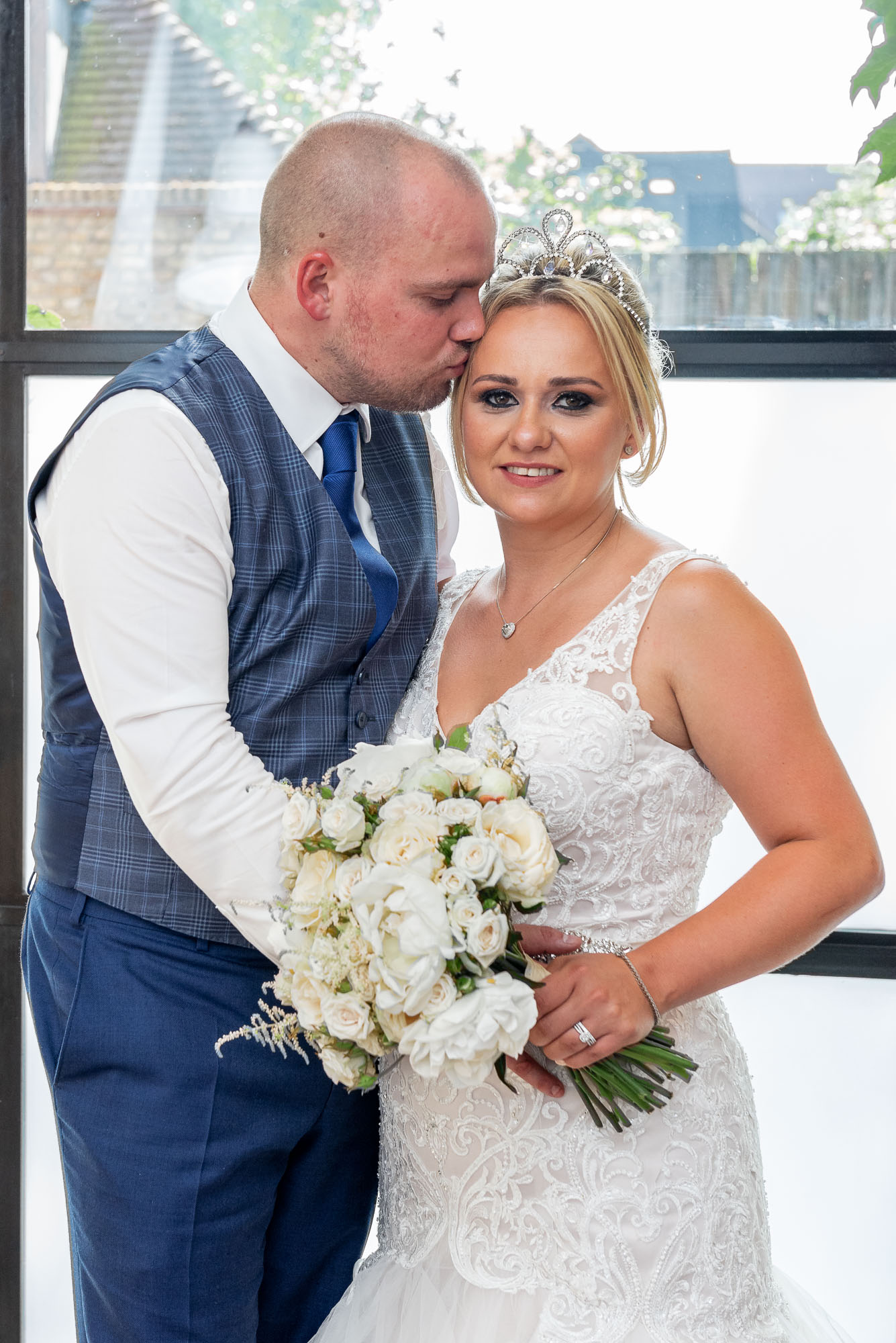 Groom kissing bride on forehead at Bluebird Chelsea wedding reception