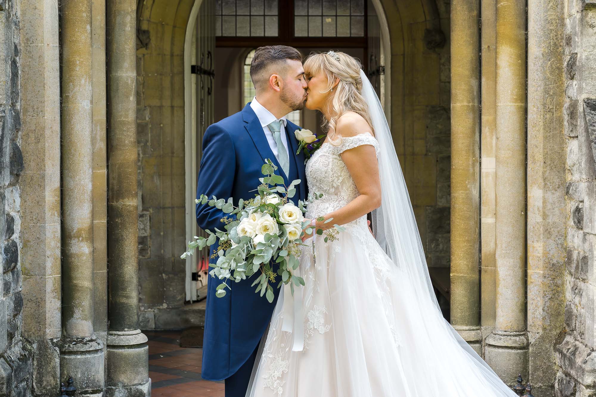 Bride and groom kissing in front of St John the Evangelist Church, Bexley, Kent