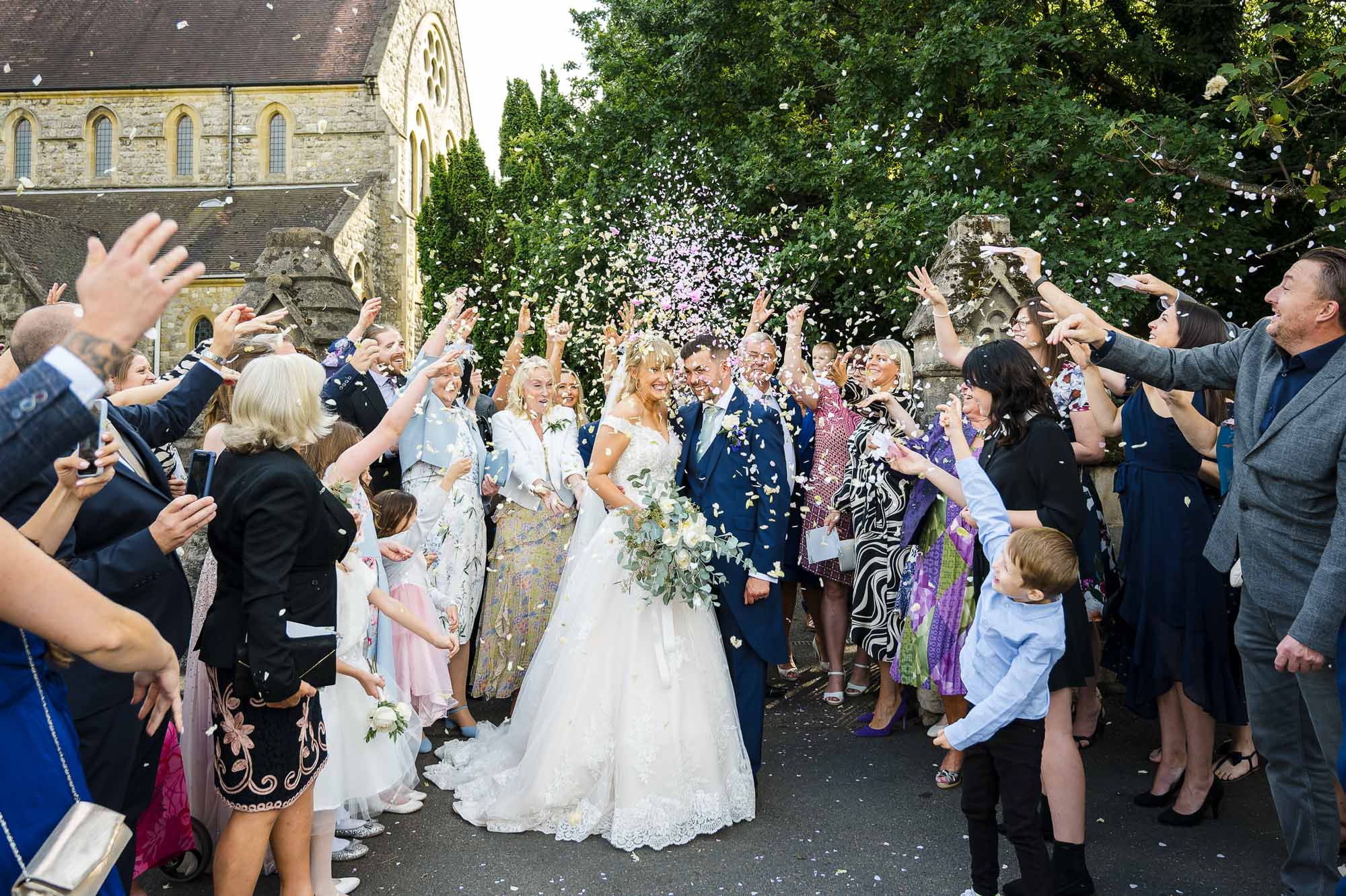 Bride and groom being showered in confetti in the grounds of St John the Evangelist Church, Bexley, Kent